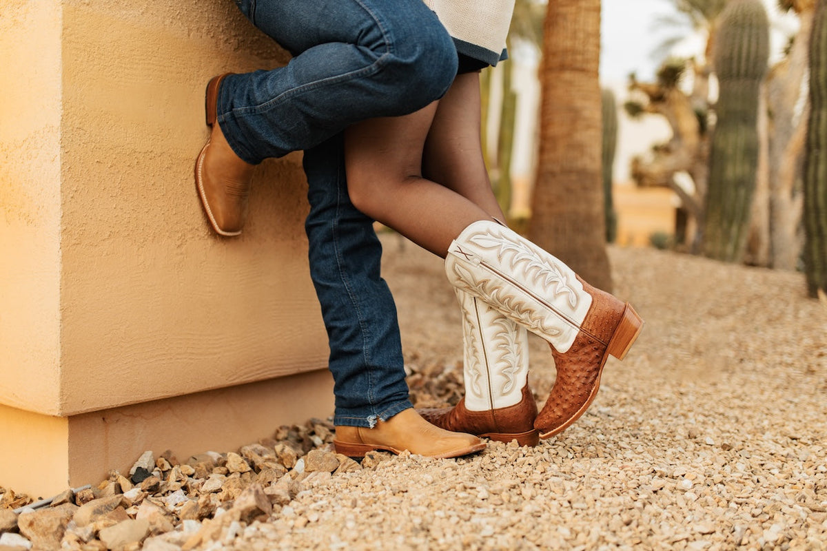 Couple wearing boots, leaning against a wall