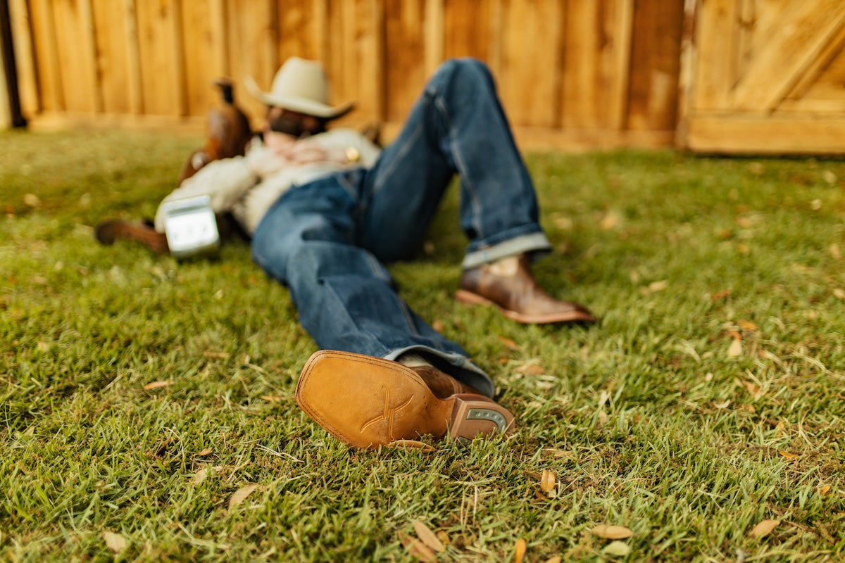 Cowboy napping on saddle with Twisted X boots