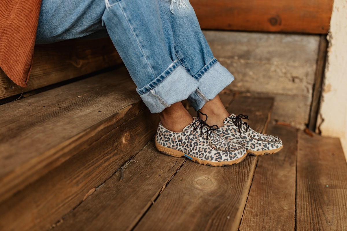 Girl seated on steps wearing Twisted X leopard print boat shoes