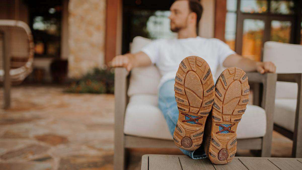 A man sitting with his feet propped up wearing Twisted X